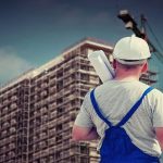 un homme de dos, face à un immeuble en rénovation