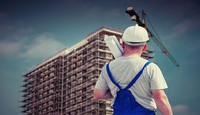 un homme de dos, face à un immeuble en rénovation