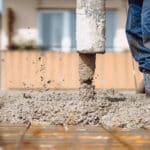 worker pouring concrete with automatic pipe pump. details of construction site and close up details of worker workwear