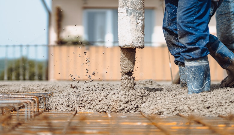 worker pouring concrete with automatic pipe pump. details of construction site and close up details of worker workwear