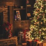 Sapin vert décoré d'une guirlande et de boules de Noël. Au pied du sapin, il y a des cadeaux.