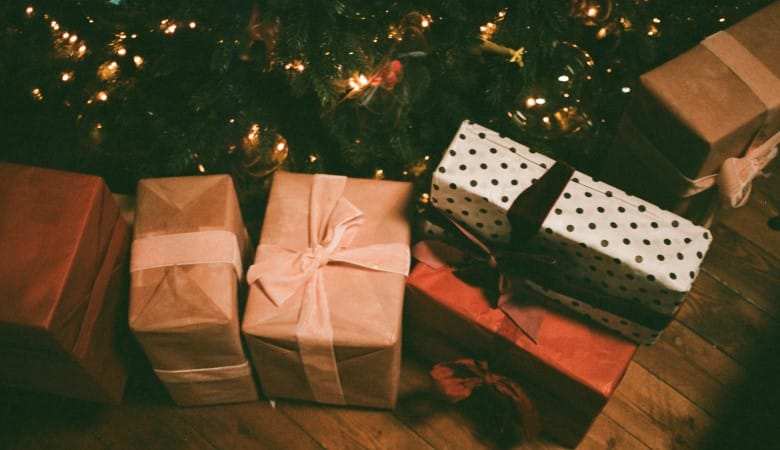 Cadeaux emballés avec du papier-cadeau et des rubans, posés au pied du sapin.