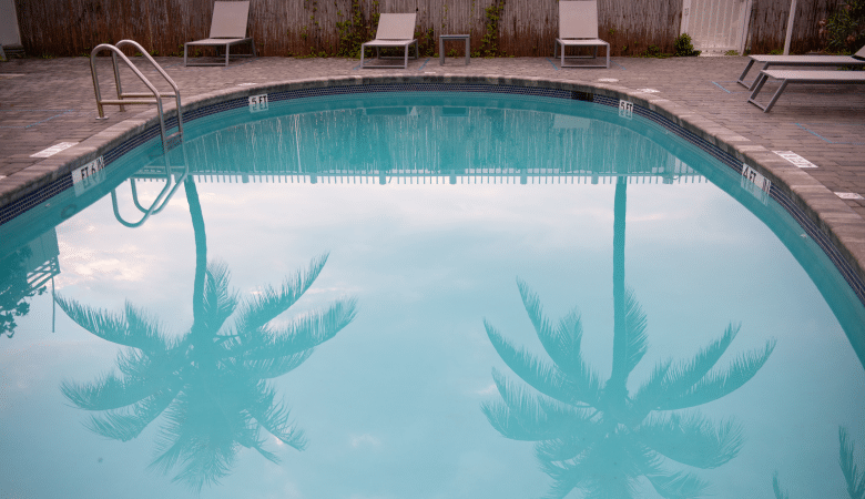 Piscine ouverte avec des palmiers qui se reflètent dans l'eau