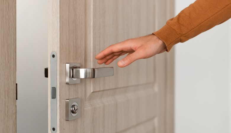 Personne qui souhaite fermer une porte d'entrée beige entre-ouverte