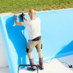 Un travailleur pose un revêtement sur les parois d'une piscine creusée.