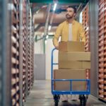 homme qui transporte des cartons remplis à l'aide d'un cadis