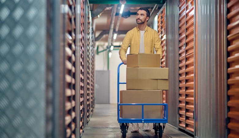 homme qui transporte des cartons remplis à l'aide d'un cadis