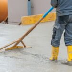 Une personne en tenue de chantier en train de lisser du béton sur un chantier