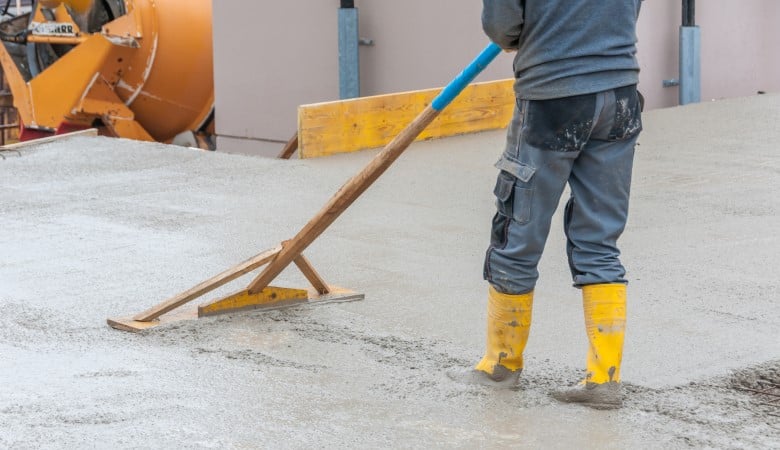 Une personne en tenue de chantier en train de lisser du béton sur un chantier