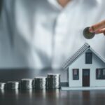 Pile de pièce à côté d'une maison miniature