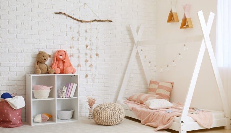 chambre d'enfant décorée dans les tons blancs, beiges, roses et marrons. On voit un lit une place à droite et un meuble de rangement à gauche.