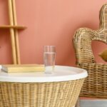 Verre d'eau et livre sur une table en rotin dans un salon