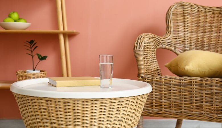 Verre d'eau et livre sur une table en rotin dans un salon