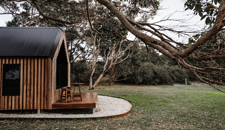 un chalet en bois dans une étendue d'herbe avec des arbres.