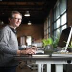 Un homme souriant sur son bureau minimaliste.