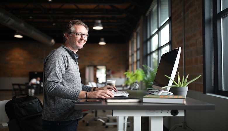 Un homme souriant sur son bureau minimaliste.