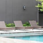 Une piscine d'extérieur en premier plan avec trois transats en arrière-plan.