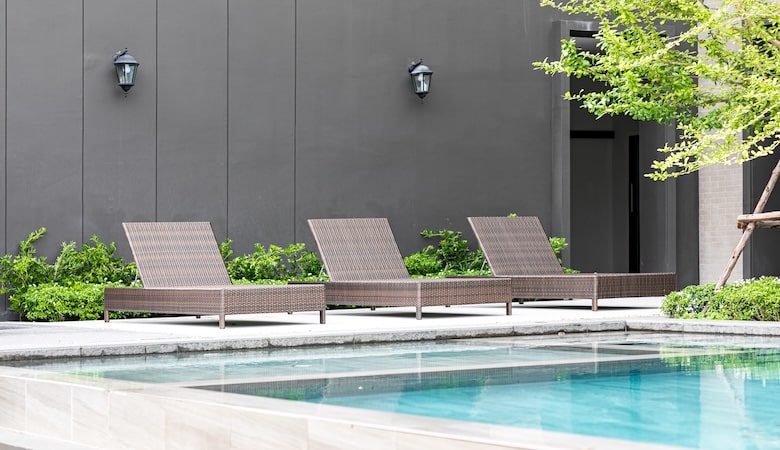 Une piscine d'extérieur en premier plan avec trois transats en arrière-plan.