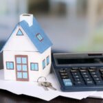 Maison-jouet et calculatrice sur une table, gros plan