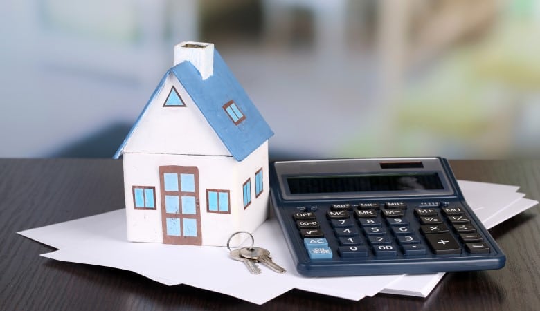 Maison-jouet et calculatrice sur une table, gros plan