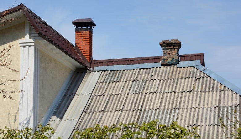 La toiture est en ardoises amiantées. Ancienne maison attenante à la nouvelle. Vieilles ardoises et cheminée.