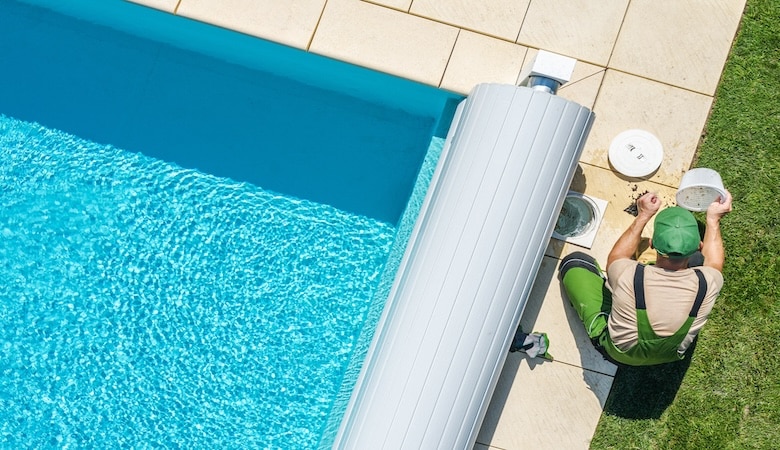 Vu d'en haut d'une piscine, avec un technicien changeant le filtre.