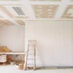 Un logement en rénovation. Une pièce vide avec une échelle et des murs peints en blanc