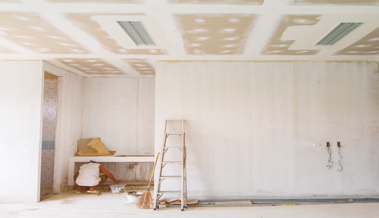 Un logement en rénovation. Une pièce vide avec une échelle et des murs peints en blanc
