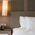 Vu sur un lit élétrique et son chevet où se trouvent une télécommande et d'autres gadgets.