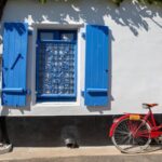 vieux vélo rouge face à une façade dans les rues d'un village de vendée, noirmoutier ou l'île de ré en france.