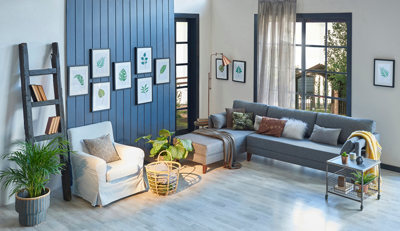 Chambre moderne bleue, canapé gris, couverture jaune et cadre en feuilles, lampe, décoration d'intérieur et parquet.