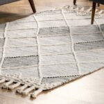 Zoom sur un tapis en laine dans les tons beiges et gris.