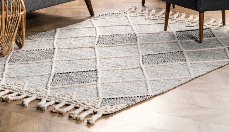 Zoom sur un tapis en laine dans les tons beiges et gris.