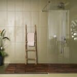 Salle de bain avec du carrelage olive au mur, une échelle décorative en bois et une douche à l'italienne.