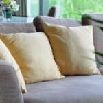 zoom sur un canapé en tissu gris, avec deux coussins jaune pâle