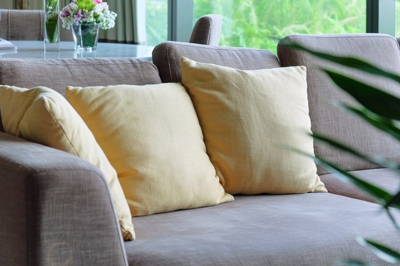 zoom sur un canapé en tissu gris, avec deux coussins jaune pâle