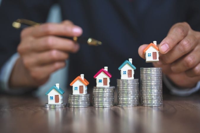 La main de la femme tient un modèle de maison mis sur la pile de pièces de monnaie avec la croissance, l'argent d'épargne pour acheter la maison et le prêt à l'investissement de l'entreprise pour le concept de l'immobilier.
