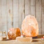 savon au sel de l'himalaya, lampe au sel gemme rose allumée et bougeoir au sel, avec bougie allumée à l'intérieur, pot avec grains de sel sur fond naturel en bois, studio. concept d'humeur zen apaisante