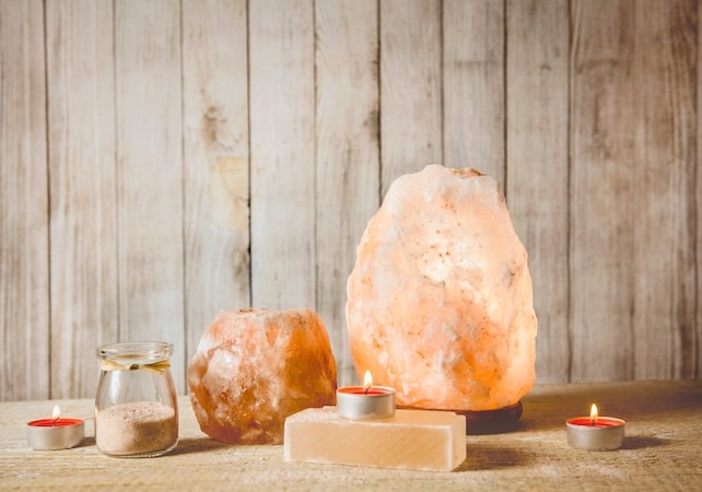 savon au sel de l'himalaya, lampe au sel gemme rose allumée et bougeoir au sel, avec bougie allumée à l'intérieur, pot avec grains de sel sur fond naturel en bois, studio. concept d'humeur zen apaisante