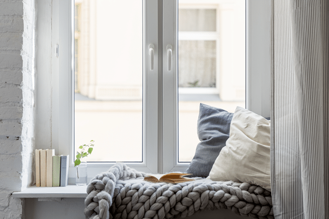 Vue sur une fenêtre avec des livres et des coussins sur le rebord.