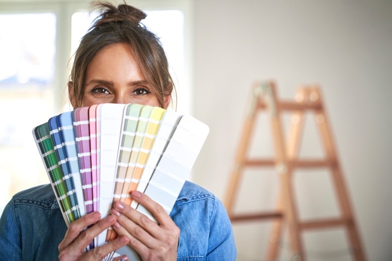 portrait en gros plan d'une femme se cachant derrière un échantillon de couleur