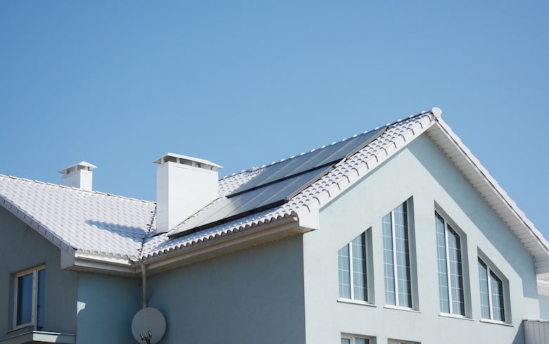 Maison passive moderne avec toit blanc et panneaux solaires pour l'économie d'énergie et l'efficacité énergétique.