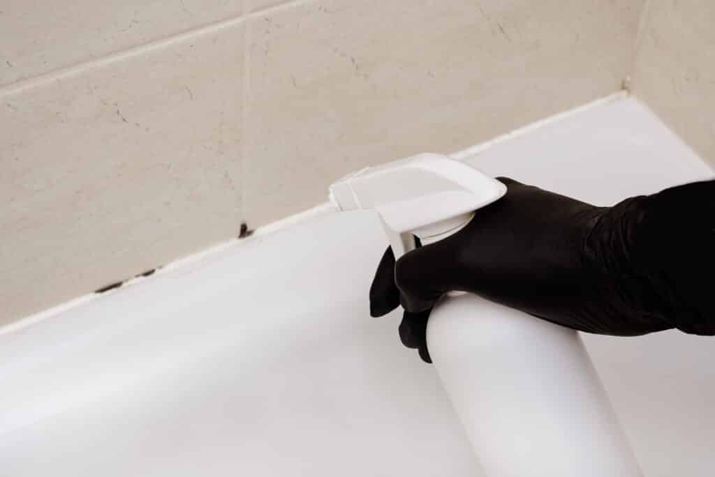 Nettoyage des joints de carrelage de salle de bain avec une brosse à dents