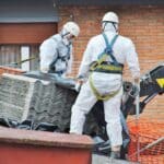 trabajadores de amianto retiran tejado de fibrocemento con una grúa, en mondragon (guipuzcoa)