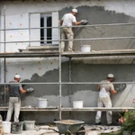 Façade de maison en cours d'isolation extérieure avec crépi et échafaudage