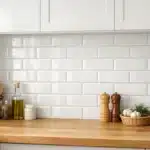 Crédence de cuisine en carrelage blanc posée entre le plan de travail et les meubles hauts